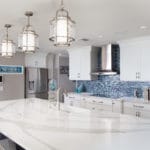 Kitchen design includes coastal, modern kitchen with a navy island and white shaker cabinets with Cambria Britannica quartz counter tops.