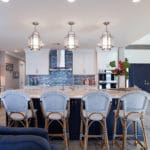 Kitchen remodel includes coastal, modern kitchen with a navy island and white shaker cabinets creates a breezy welcoming area for a crowd to gather.