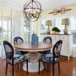 Kitchen design includes these navy floral upholstered chairs brings the outside in at this ocean side condo. A vintage inspired round dining table and sideboard create an inviting area to sit an enjoy the view.