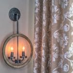 Rustic wall sconce and custom linen fabric drapes with a metallic floral design.