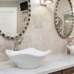 Bathroom decor includes white vessel tulip shaped sinks, quartz counter tops and weathered driftwood cabinets.