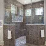Master shower remodel features a curb less entry and hexagon tile floor. Walls are clad in a porcelain tile with a mix of gray and brown tones creating a warm, inviting space. Dual shower heads offer both a rain head and wall mounted creating a spa like environment!